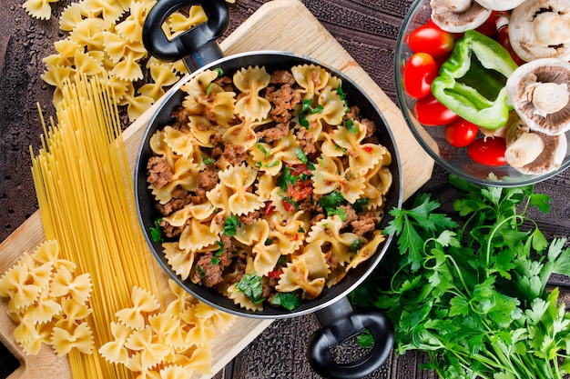 Pasto di pasta in padella con pasta cruda, funghi, pepe, prezzemolo, pomodoro