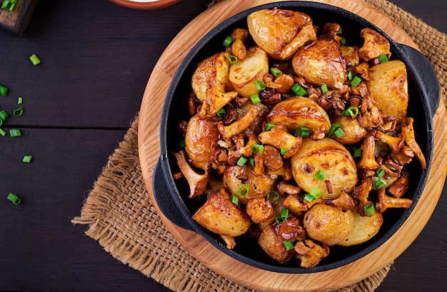 Patate al forno con aglio, erbe e finferli fritti in una padella di ghisa. Vista dall'alto