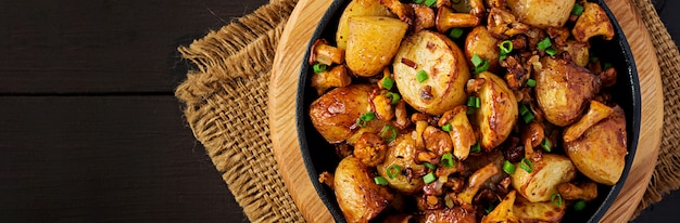 Patate al forno con aglio, erbe e finferli fritti in una padella di ghisa. Vista dall'alto