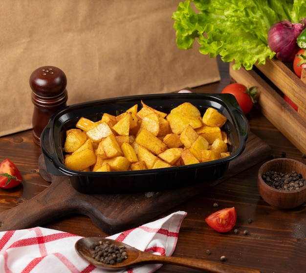 Patate fritte con erbe da asporto in contenitore nero.