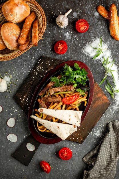 Patate fritte con pezzi di carne fritta in una pentola di terracotta