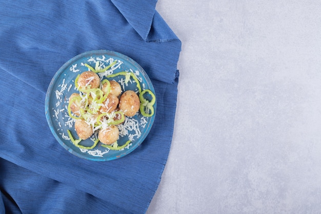 Patate fritte decorate con formaggio e pepe su piatto blu.