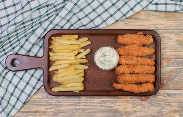 Patate fritte e bastoncini di pollo con salsa bianca.