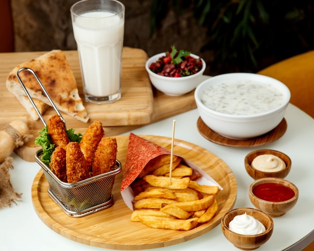 Patate fritte e pepite di pollo in pastella su un bordo di legno