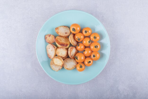 Patate fritte e pomodori sul piatto blu.