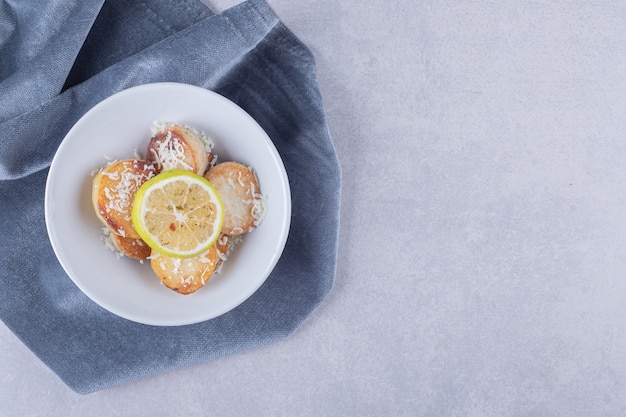 Patate fritte guarnite con formaggio grattugiato e limone sul piatto bianco.