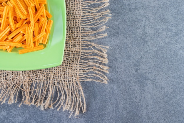 Patate fritte saporite su un piatto su struttura sulla superficie di marmo