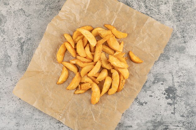 Patate fritte su carta oleata su uno sfondo di pietra.