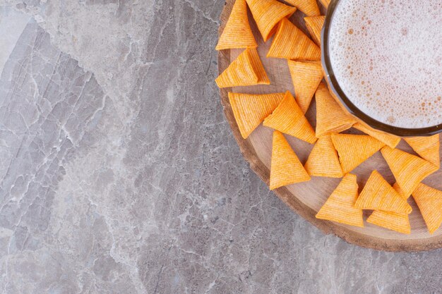 Patatine croccanti con birra fredda su un pezzo di legno