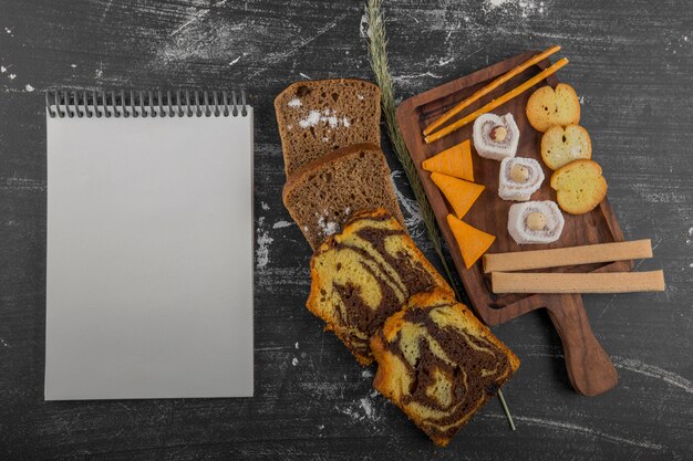 Patatine fritte con prodotti di pasticceria su un piatto di legno e fette di pane da parte con un libretto di ricevute