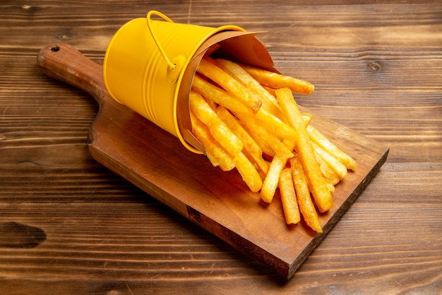 Patatine fritte di vista frontale dentro il piccolo cestino sul pasto marrone dell'hamburger del fast food della patata della scrivania