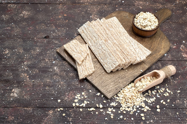 Patatine fritte e cracker di vista superiore formate a lungo con farina d'avena cruda sullo scrittorio di legno