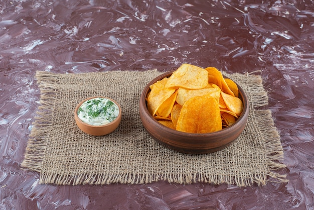 Patatine fritte e yogurt croccanti in piatti su struttura, sulla tavola di marmo.