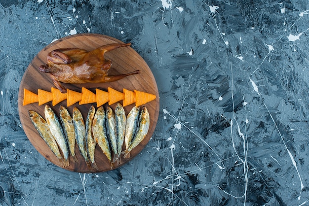 Patatine, pollo alla griglia e pesce su una tavola, sullo sfondo di marmo.