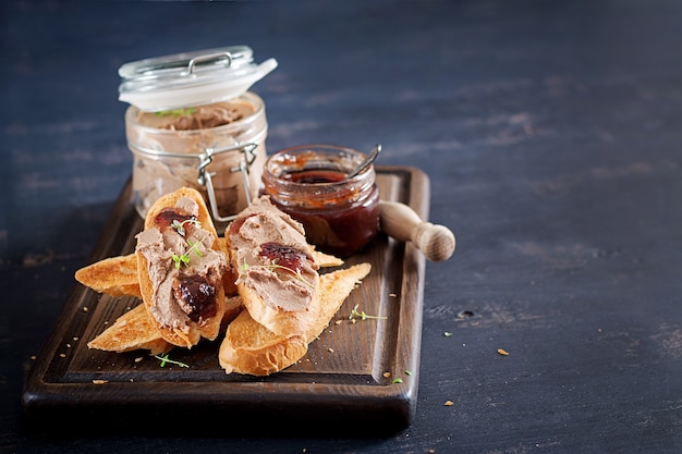 Patè di fegato fatto in casa di pollo in barattolo di vetro con toast e marmellata di mirtilli rossi con peperoncino.