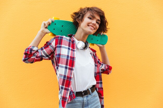 Pattino grazioso felice della tenuta dell'adolescente sulle sue spalle