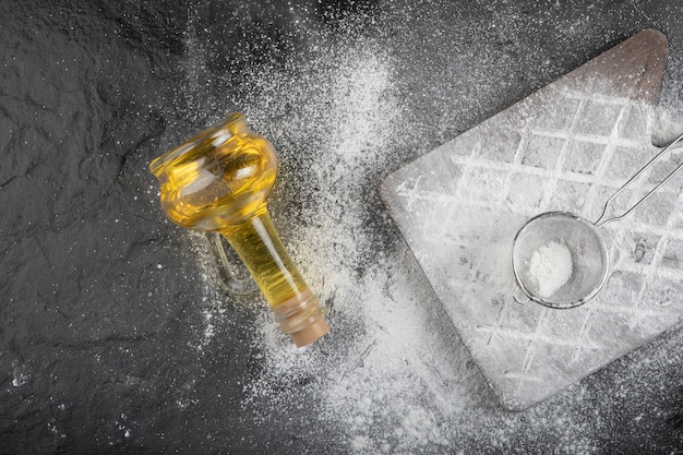 Pavimento di grano fresco versato su una tavola di legno con un bicchiere d'olio