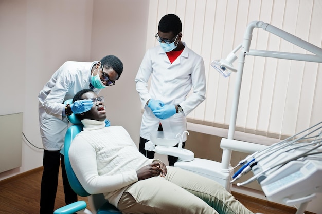 Paziente afroamericano in poltrona odontoiatrica Studio dentistico e concetto di pratica medica Dentista professionista che aiuta il suo paziente in odontoiatria medica