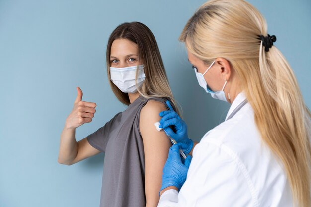 Paziente di sesso femminile con maschera medica che ottiene un vaccino