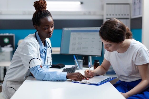 Paziente donna che firma documenti medici che discutono del trattamento farmacologico