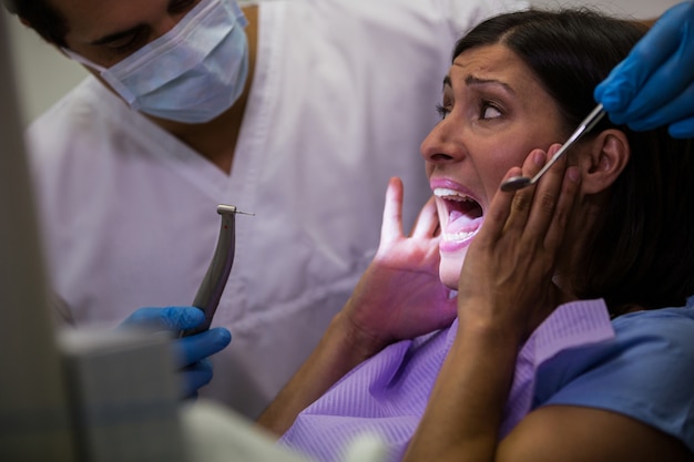 Paziente femminile spaventato durante un controllo dentale
