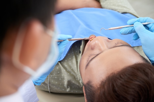 Paziente maschio asiatico che ha controllo dentale in clinica