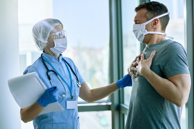 Paziente maschio con sintomi COVID19 che parla con un medico e si lamenta di mancanza di respiro in ospedale