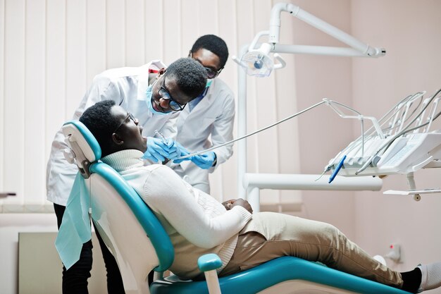 Paziente uomo afroamericano in poltrona odontoiatrica Studio dentistico e concetto di pratica medica Dentista professionista che aiuta il suo paziente in odontoiatria medica Perforazione dei denti del paziente in clinica