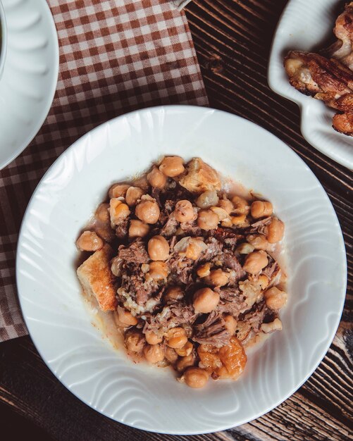 Peccato in un piatto bianco con agnello, agnello grasso, castagne e piselli