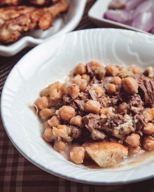 Peccato in un piatto bianco con agnello, agnello grasso, castagne e piselli