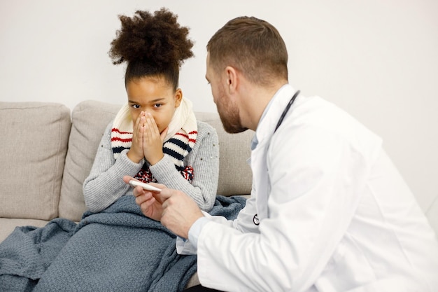 Pediatra maschio che esamina piccola ragazza nera malata