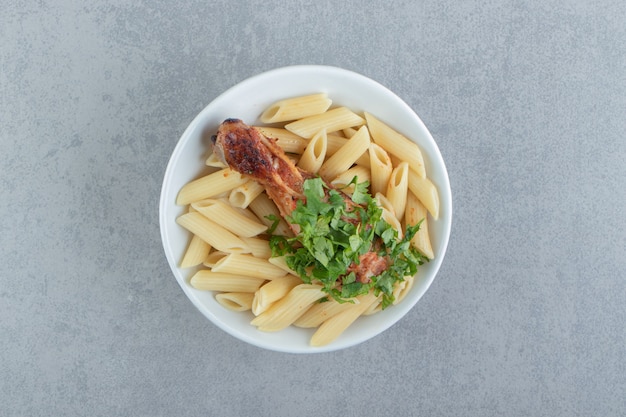 Penne con pollo arrosto in ciotola bianca.