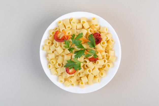 Penne con prezzemolo e fette di pomodoro in una ciotola bianca