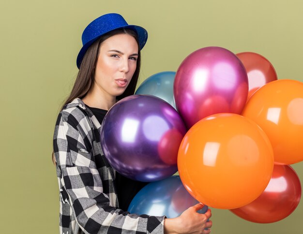 Pensando giovane bella ragazza che indossa un cappello blu con palloncini