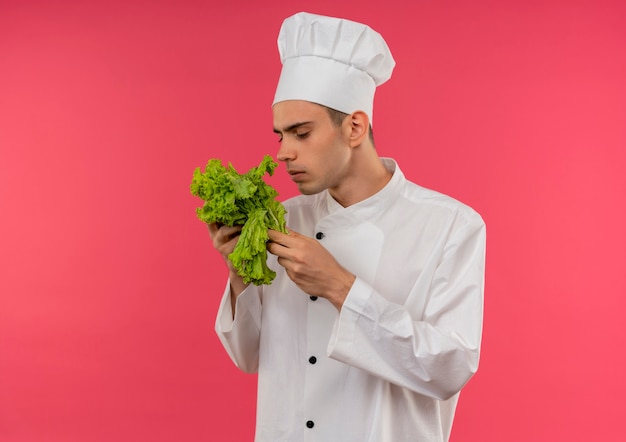 Pensando giovane cuoco maschio indossando chef uniforme holding e annusando insalata con copia spazio