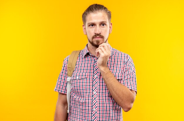 Pensando giovane studente che indossa uno zaino mettendo la mano sul mento