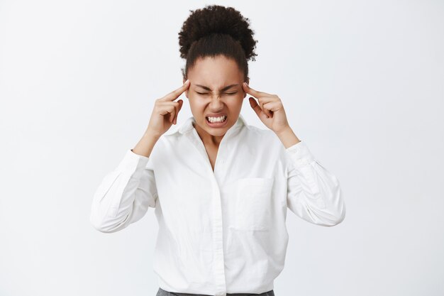 Pensare con tutta la potenza del cervello. Ritratto di donna dall'aspetto serio concentrato intenso con la pelle scura in camicia da colletto bianco, serrando i denti e sollevando la tensione mentre cerca di concentrarsi e truccare il piano