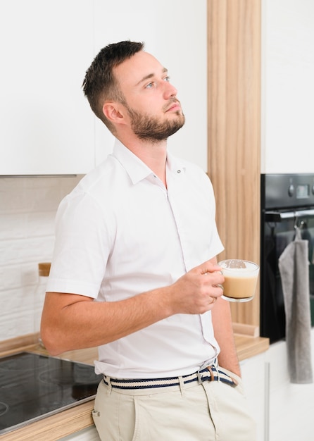 Pensatore uomo in cucina con un cappuccino