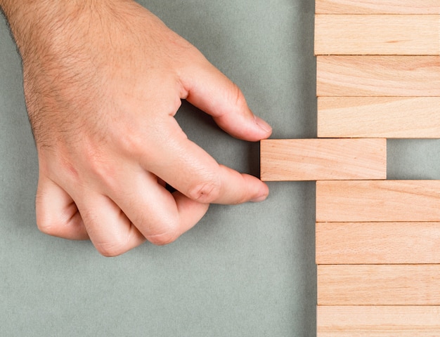 Pensiero differente e concetto differente di idea con i blocchi di legno sulla vista superiore del fondo di verde navy. uomo che fa scorrere l'elemento. immagine orizzontale