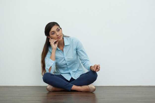 Pensieroso bella donna sul pavimento con le gambe incrociate