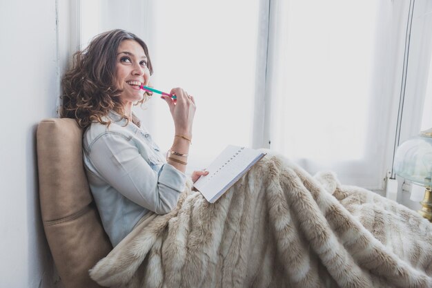 Pensieroso giovane donna con una penna in bocca