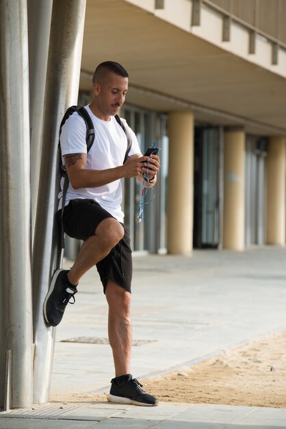 Pensive giovane atleta messaggio di testo durante il riposo