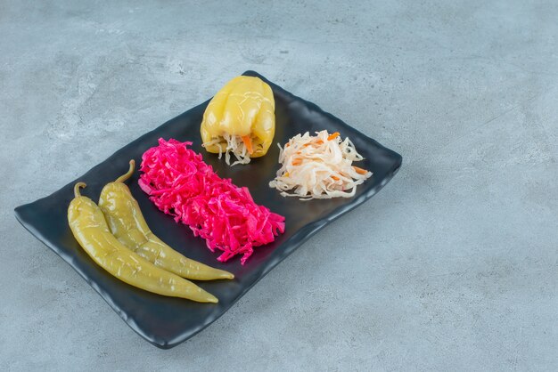Pepe e crauti fermentati su un piatto di plastica, sul tavolo blu.