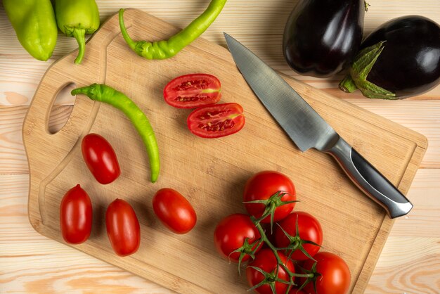 Peperoncini rossi verdi e pomodori affettati sulla tavola di legno