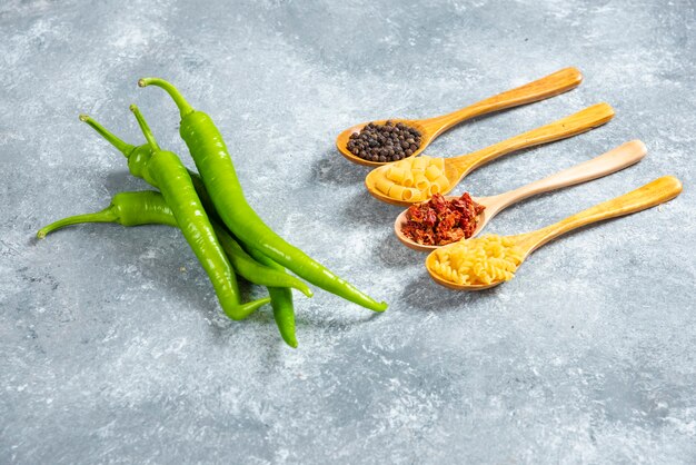 Peperoncini verdi e cucchiai di pasta di legno.