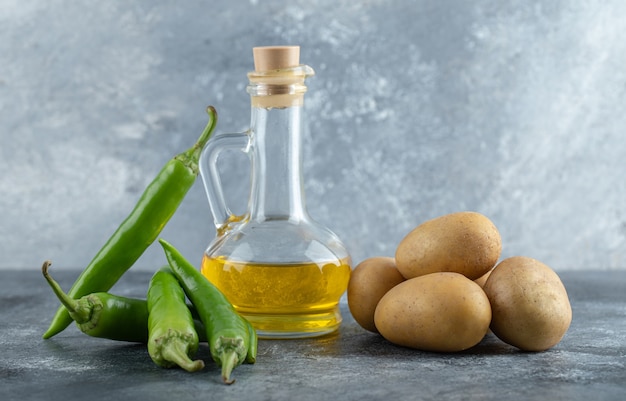 Peperoncini verdi, olio d'oliva e patate su fondo di marmo