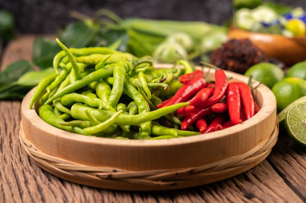 Peperoncino fresco su un vassoio di legno con limone e foglie di lime kaffir.