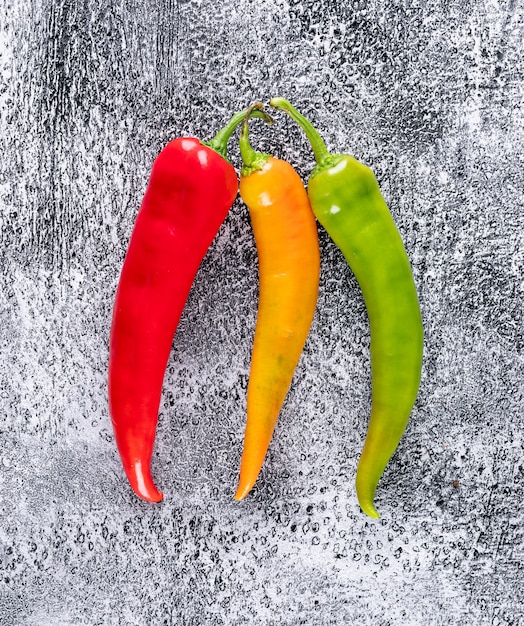 Peperoncino giallo e verde rosso di vista superiore sul verticale di pietra grigio