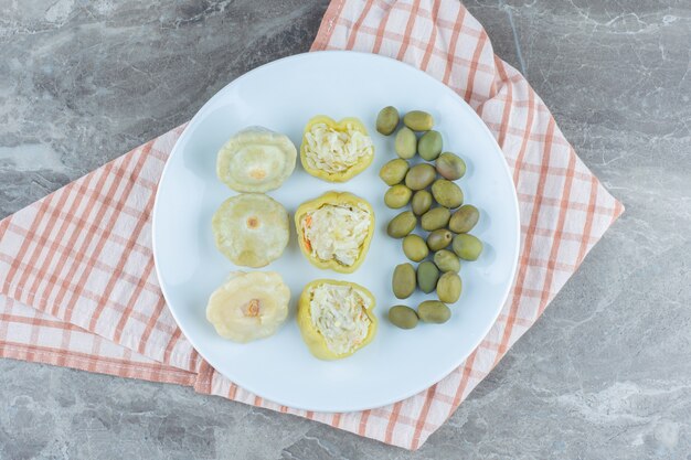 Peperone verde e oliva riempiti sul piatto bianco.