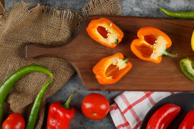 Peperoni di colore arancio del mezzo taglio su un bordo di legno.